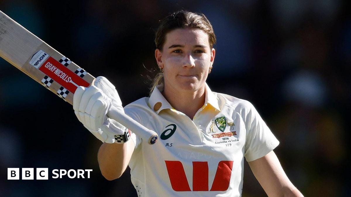 Australia batter Annabel Sutherland raises her bat to celebrate reaching a Test century against India
